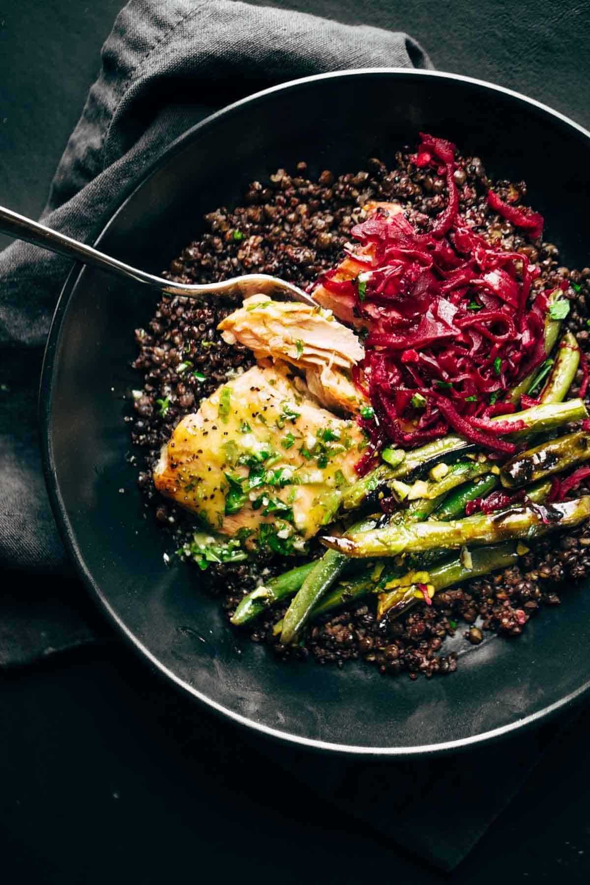 Salmon in a bowl with lentils, sauerkraut, and green beans.