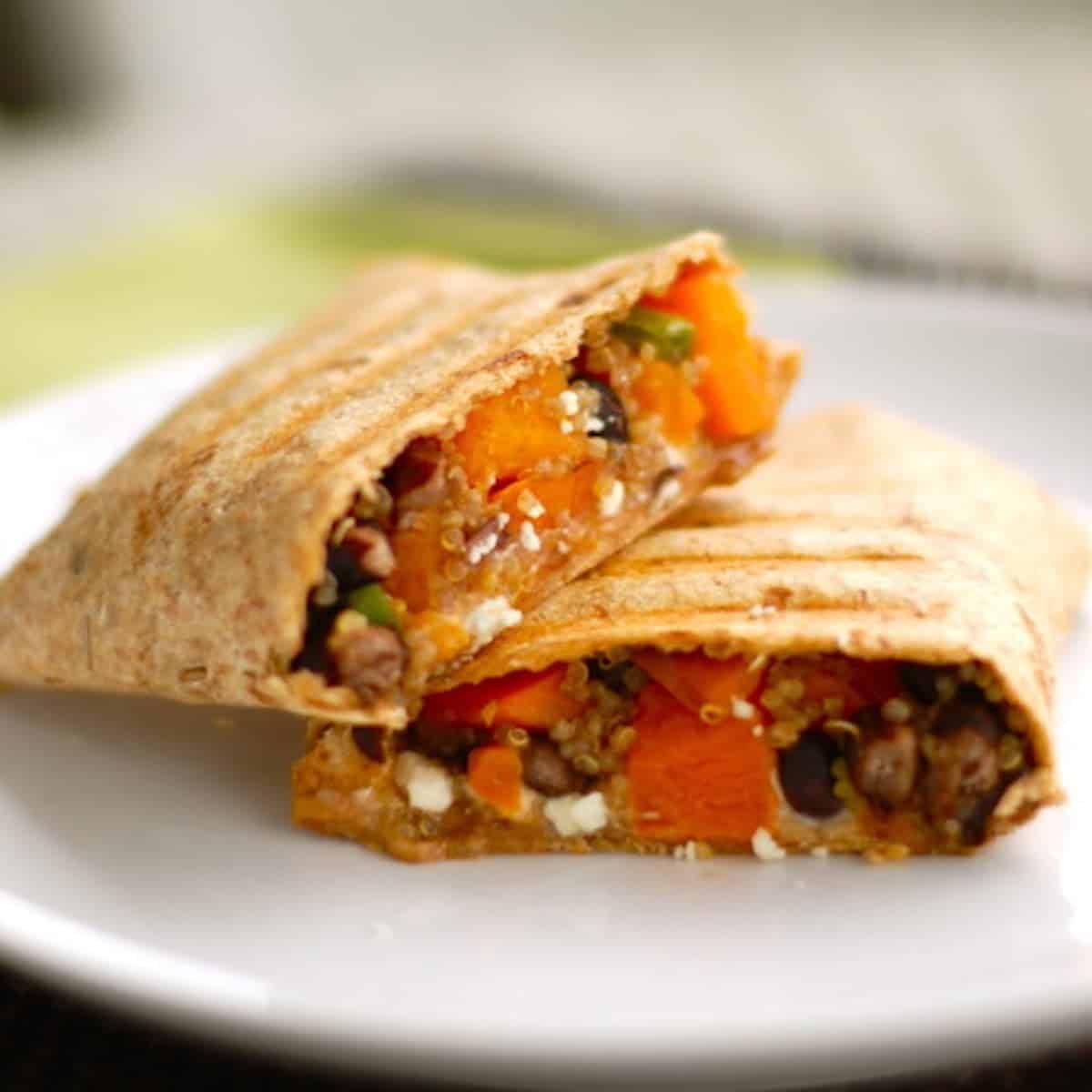 Butternut squash black bean wrap sliced down the center on a white plate.